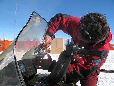 [FixWindshield.jpg]
One of the main activities of some [anonymous] people seems to have been breaking snowmachines. At night they are connected to a horizontal pole via an electrical outlet so their engines stay warm, and in the morning many people with not enough coffee in their veins seem to forget the plug and drive away, crashing the pole on themselves. Here Antonio, the mechanics, fixes a broken windshield with aluminum tape.