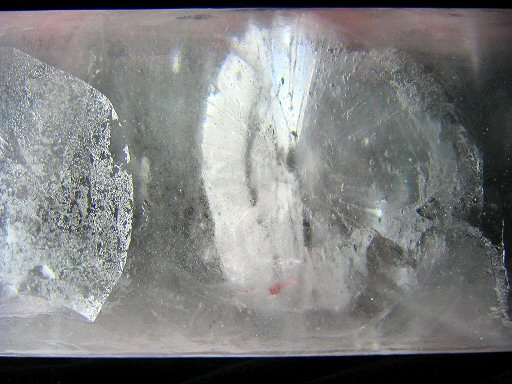 [IMG_1538_CrystalBoundaries.jpg]
A very large ice crystal is visible inside this ice core; more exactly the boundaries between them is visible, the one on the left because some air got in during the removal process, and the boundary on the right is visible in incident light. This crystal is a good 30cm in diameter (Photo courtesy of EPICA).