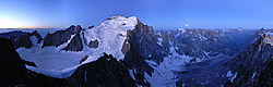 20060711-05-EcrinsEarlyPano - The full moon setting behind the Barre des Ecrins at 5am, Oisan. From left to right: the Glacier Blanc, the Pelvoux in the back, the Barre, the Dome des Ecrins, the Bonne Pierre glacier with the moon above it and La Bérarde as a tiny point of light down the glacier.
[ Click to go to the page where that image comes from ]