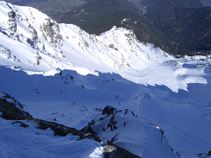 Skiers going down the north couloir of the Grand Colon