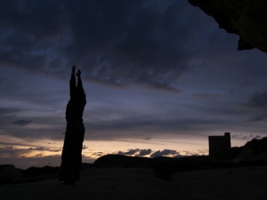 Yoga practice above a darkening Xlendi bay