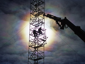 Irridescent clouds behind people working on the American Mast